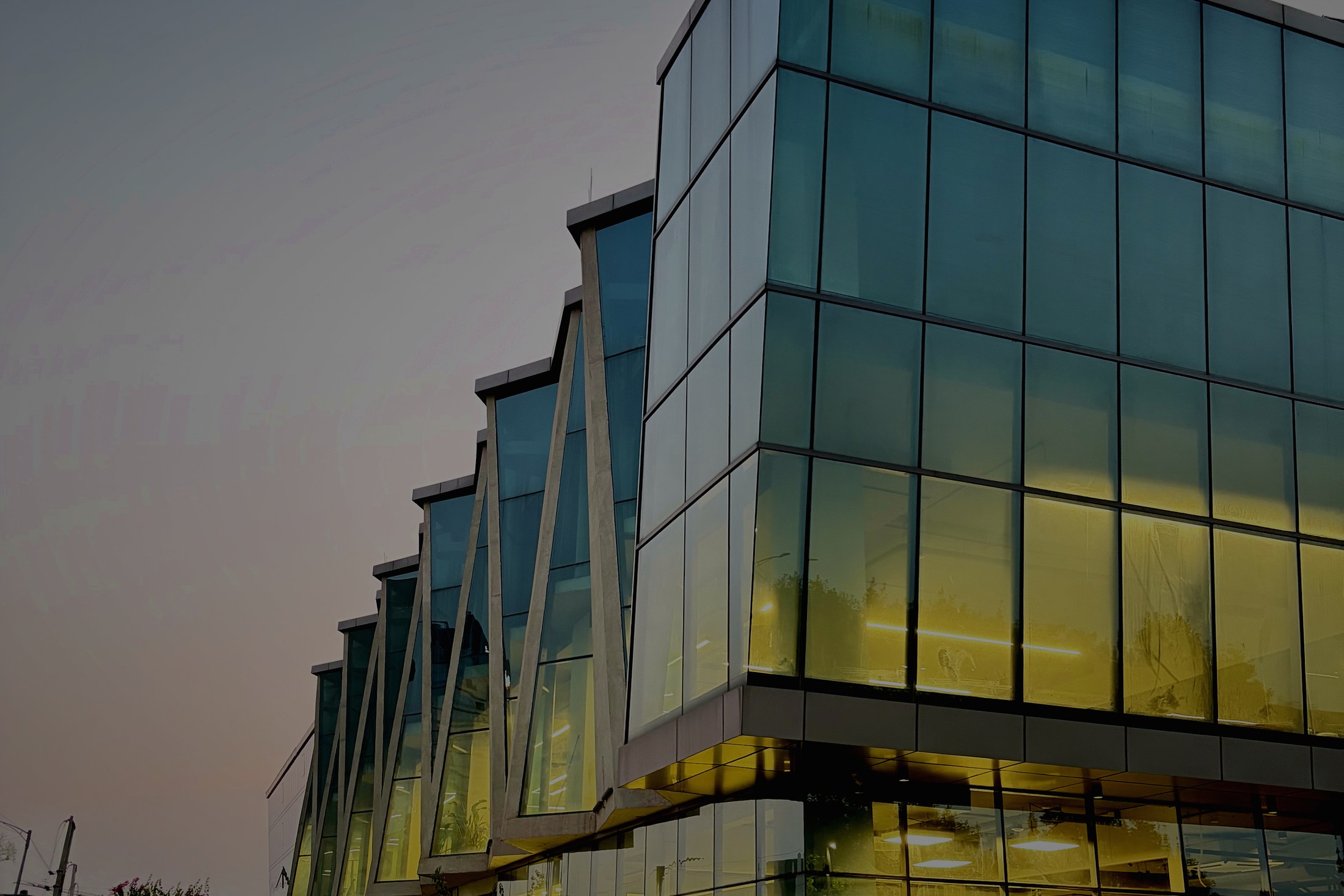 The campus facade at dusk, the studio floors lit inside the glass