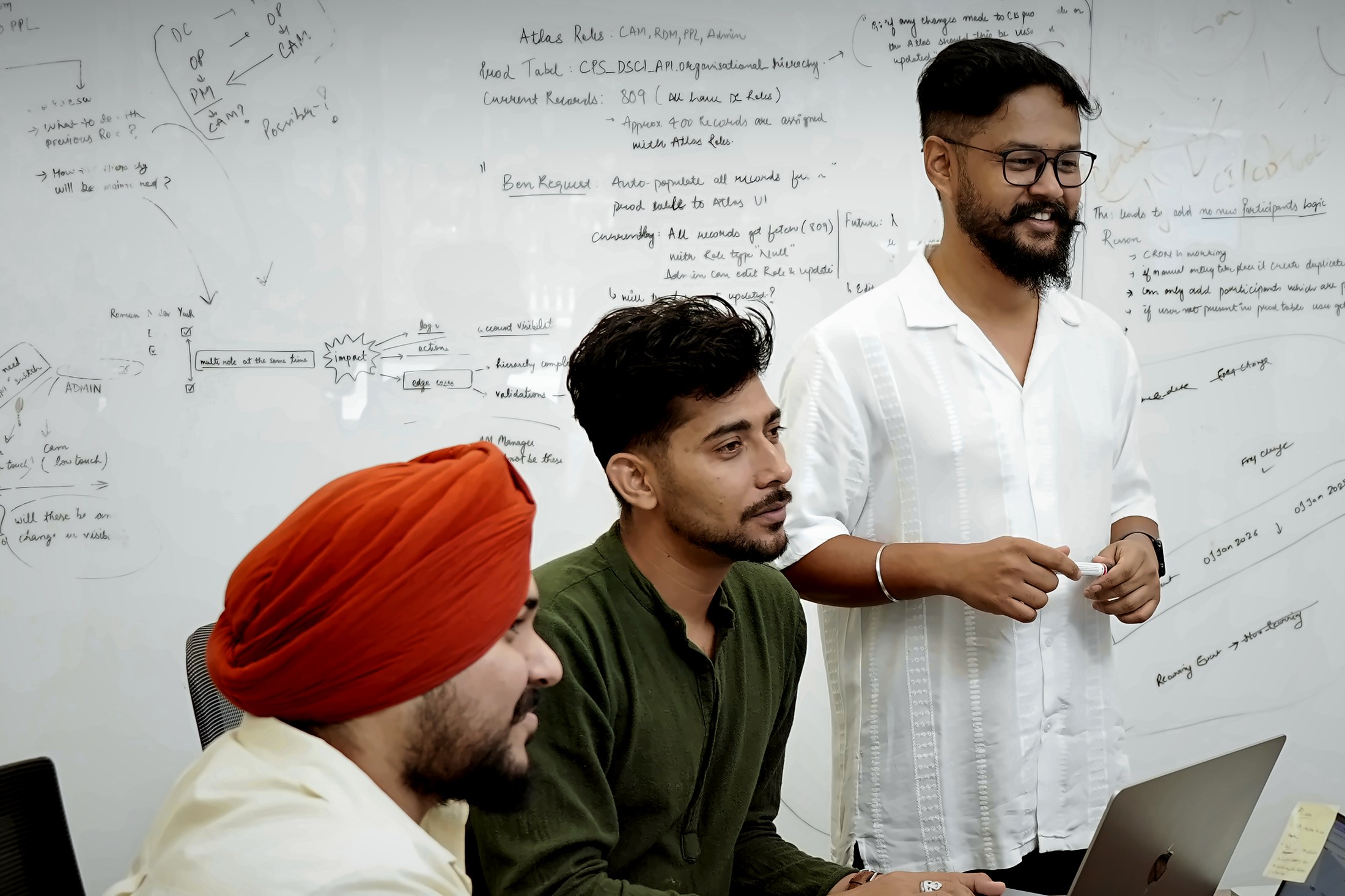 Three of the team working a problem through at the whiteboard, Alpha IT City, Mohali